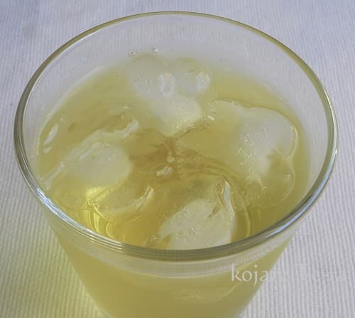 ガラスに入った緑茶に入れたラズベリー型の氷のアップ